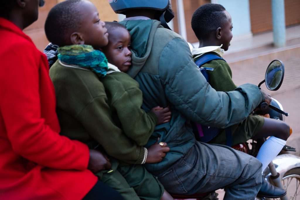 Children ride boda bodas to school in Kampala without helmets. A 2023 MakSPH–Bloomberg road safety report found helmet use was low among riders (39%) and almost non-existent among passengers (2%). Photo by Katumba Badru.