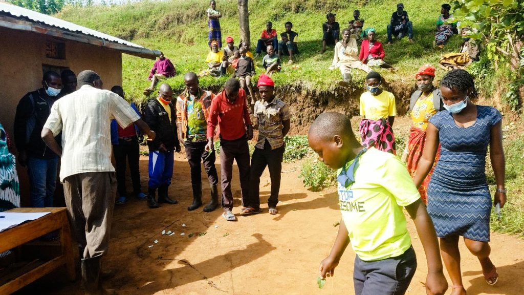 Dressed in blue, a family member and student works alongside community residents to map areas affected by open defecation, fostering collective awareness and action. Makerere University School of Public Health Communications Office, Graduation Profiles Series, 76th Graduation Ceremony, Moses Ntaro, “Effect of Student Community Engagement on Open Defecation-Free Status,” Kampala Uganda, East Africa.