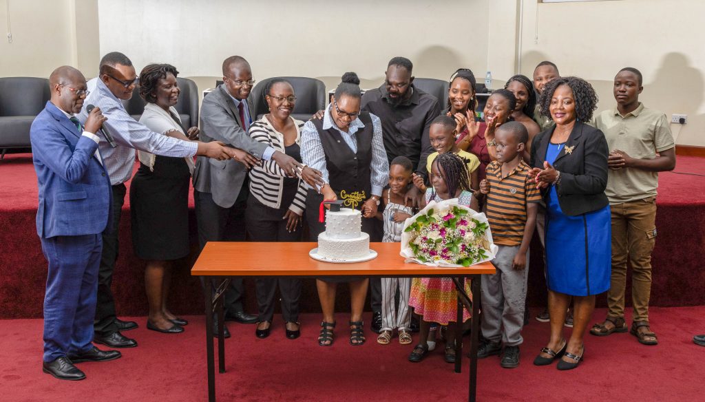 Dr. Nakisita joined by supervisors, examiners and family in a ceremonial cake cutting. Makerere University School of Public Health Communications Office, Graduation Profiles Series, 76th Graduation Ceremony, Olivia Nakisita, āMaternal Health Services for Adolescent Refugees in Urban Settings in Uganda: Access, Utilisation, and Health Facility Readiness,ā Kampala Uganda, East Africa.