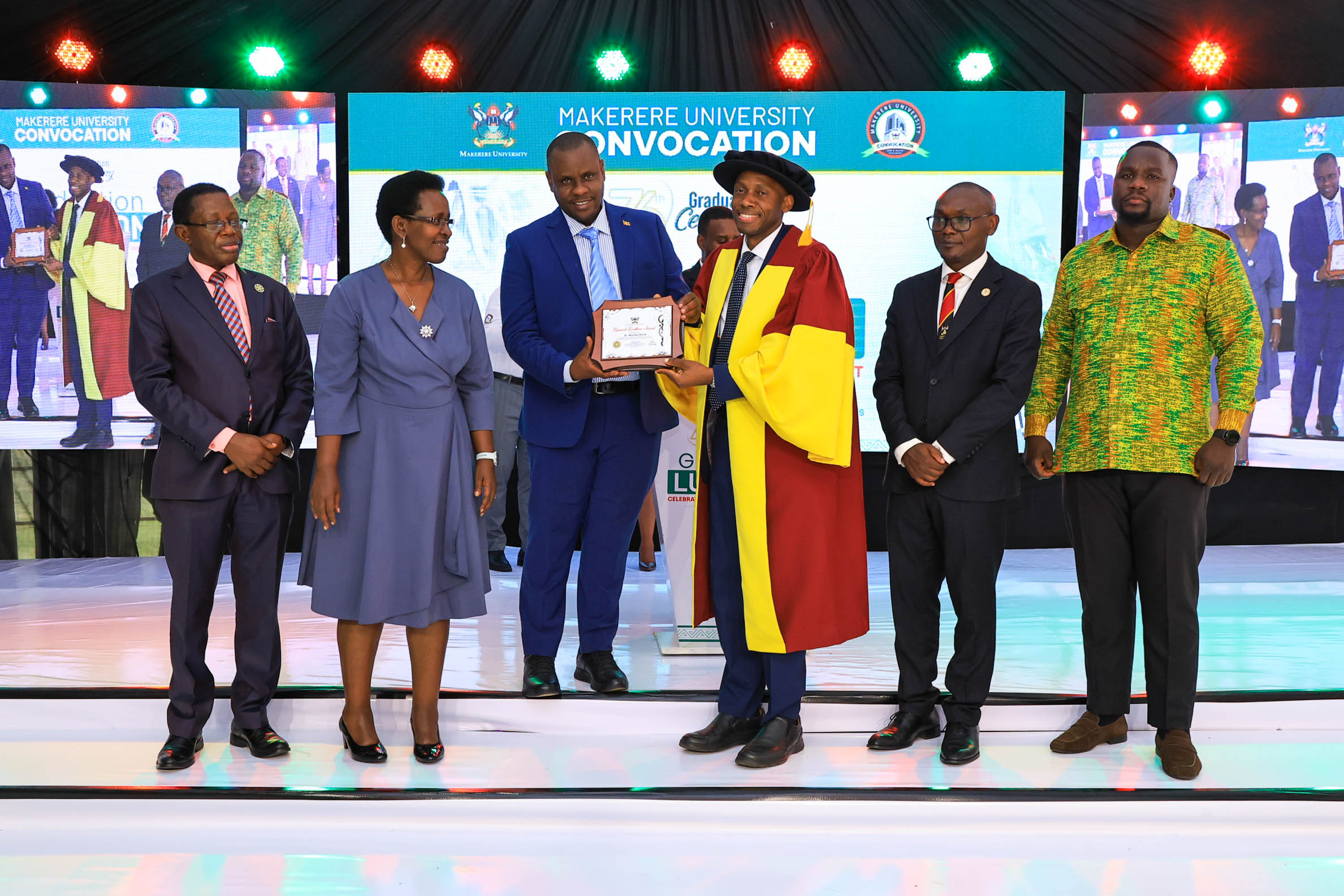Dr. David Musoke, Associate Professor of Disease Control at MakSPH, receives a plaque recognising his scholarly work from Hon Balaam Barugahara Ateenyi, Minister of State for Youth and Children Affairs, during the Mak Convocation luncheon. Looking on are Prof Buyinza Mukadasi, Academic Registrar; Dr Diana Atwiine, Permanent Secretary, Ministry of Health; Convocation Chairperson Mr George Turyamureeba Mugabi; and NRM National Youth Chairperson Mr Collins Tanga. 76th Graduation Ceremony, Day 2, School of Public Health (MakSPH) Vice Chancellors Research Excellence Awards. 25th February 2026, Makerere University, Kampala Uganda, East Africa.