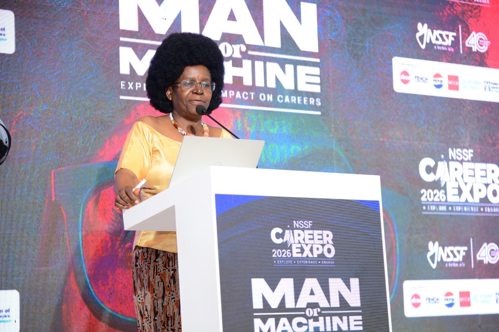 Hon. Dr. Monica Musenero delivering a keynote address on day one of the career fair. Three-day Careers Fair 2026, bringing together students, industry leaders, and policymakers to discuss the future of work in the era of Artificial Intelligence (AI), Day 1 held under the theme “Machine vs. Man” and sponsored by the National Social Security Fund (NSSF), 11th March 2026, Yusuf Lule Central Teaching Facility Auditorium, Makerere University, Kampala Uganda, East Africa.
