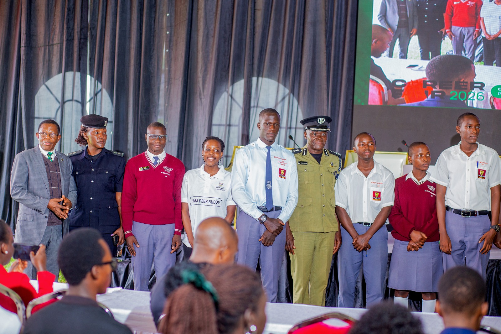 Prof. Buyinza Mukadasi (L) with CP Anatoli Muleterwa (4th R) and Alaso Immaculate Emily (2nd L) pose for a group photo with some of the secondary school students that attended Day 3 of the Careers Fair on 13th March 2026. Three-day Careers Fair 2026, bringing together students, industry leaders, and policymakers to discuss the future of work in the era of Artificial Intelligence (AI), Day 3, Grand Finale, held under the theme “Connecting Potential to Purpose: Partnerships for Sustainable Impact”, 13th March 2026, Freedom Square, Makerere University, Kampala Uganda, East Africa.