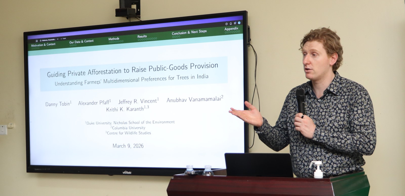 Dr. Danny Tobin presenting. Displayed on the screen is his study title. Environment for Development (EfD) Centre research seminar by UK-based Duke University Postdoctoral Scholar Dr. Danny Tobin's study titled, “Guiding Private Afforestation to raise public-Goods Provision : Exploring Farmers preferences for trees within an NGO Tree planting program in Southern India” 9th March 2026, Yusuf Lule Central Teaching Facility, Makerere University, Kampala Uganda, East Africa.