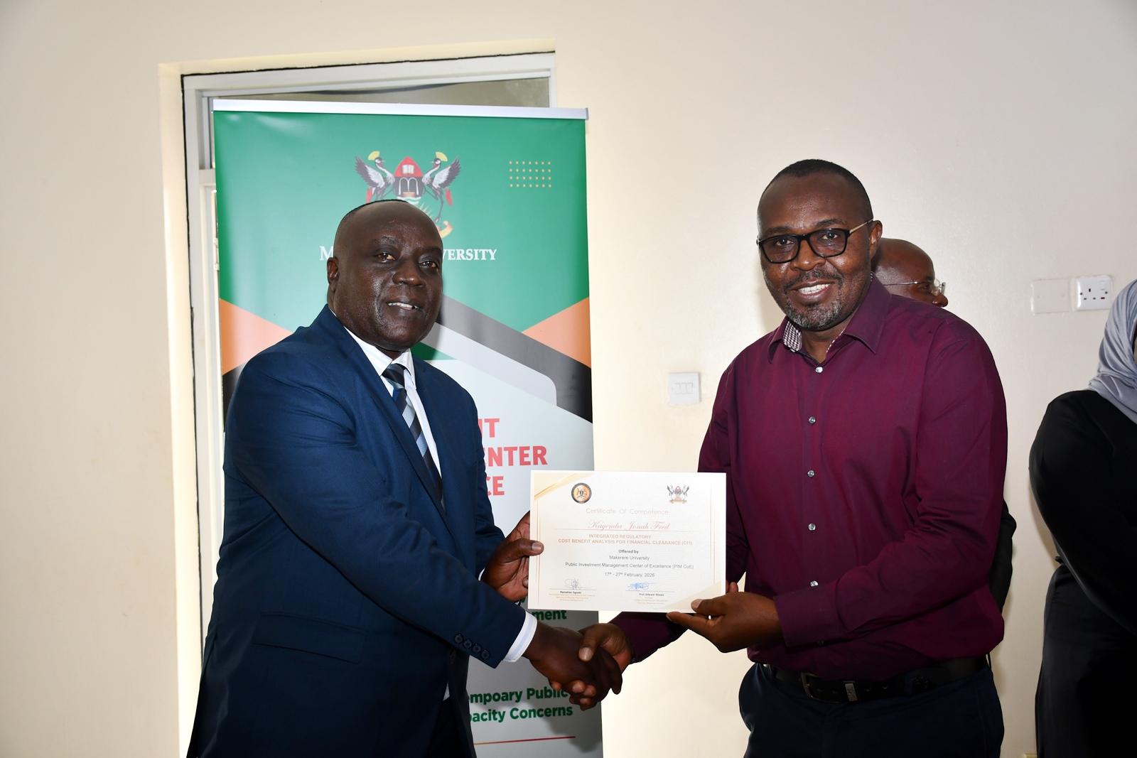 Commissioner Mwanja presents a certificate to one of the participants Kayemba Jonah Fred. Ministry of Finance, Planning and Economic Development (MoFPED), in partnership with the Public Investment Management Centre of Excellence (PIM CoE), Makerere University, Kampala in collaboration with the Infrastructure and Social Services Department (ISSD) and the National Planning Authority (NPA), successful completion of two-week intensive training in the Certificate of Financial Implications (CFI) – Integrated Regulatory Cost-Benefit Analysis (IRCBA). 27th February 2026, Pearl on the Nile Hotel, Jinja, Uganda, East Africa.