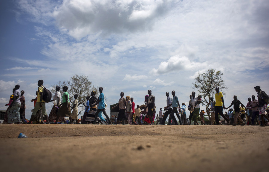 Displaced families walk toward registration and settlement areas on arrival at Imvepi Refugee Settlement in northern Uganda. Komakech’s research highlights how health systems must adapt to support both refugees and host communities during arrival, settlement, and eventual repatriation, emphasising planning for continuity of care and sustainable services. Photo: Kieran Doherty / Oxfam. Makerere University School of Public Health Communications Office, Graduation Profiles Series, 76th Graduation Ceremony, Dr. Henry Komakech, “Effects of the Repatriation of Refugees on the Health Services of the Host Populations in the West Nile Districts of Arua, Moyo, and Adjumani,” Kampala Uganda, East Africa.