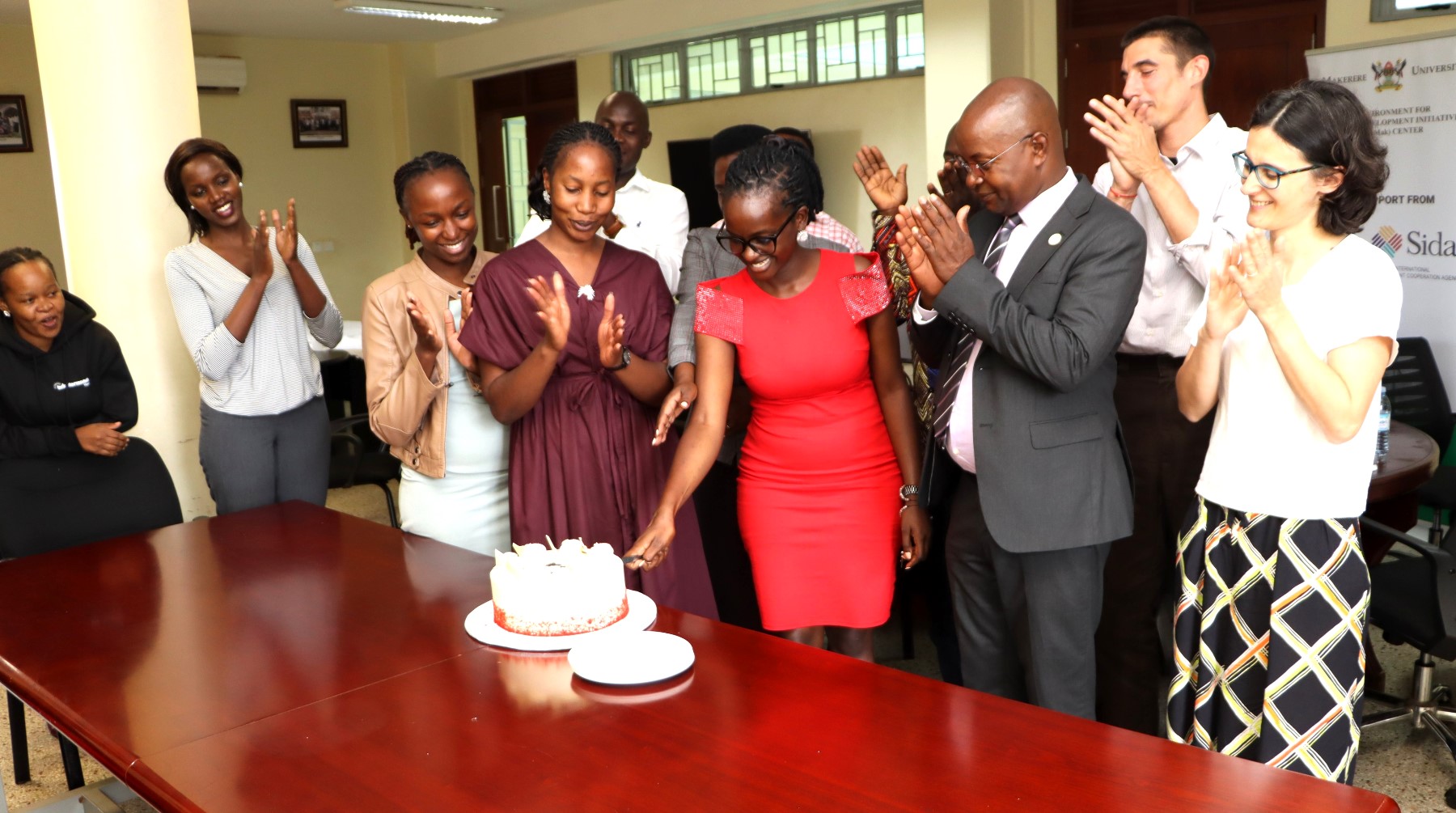 Ruth Asiimwe (in Red dress) cuts the cake in honor of her departure on 16th April 2026. Environment for Development (EfD) Centre bids farewell to third intern, Ruth Asiimwe, who secured a position with the African Development Bank in Juba South Sudan, 16th April 2026, Yusuf Lule Central Teaching Facility, Makerere University, Kampala Uganda, East Africa.