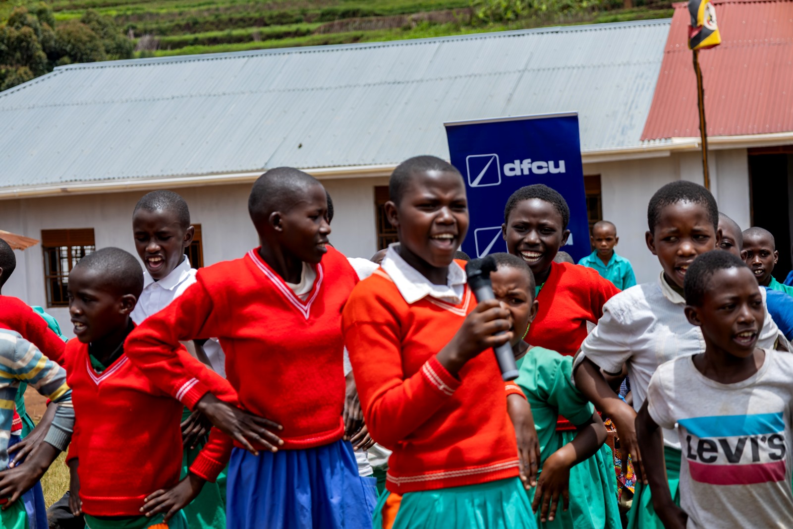 Pupils perform for guests. Mastercard Foundation Scholars Program at Makerere University Giveback, in partnership with dfcu Bank, handover five-classroom block equipped with 60 bench desks, four-stance modern pit latrine, and a 10,000-litre rainwater harvesting system on 1st April 2026 to Bwera Primary School in Kabale District, Uganda, East Africa.