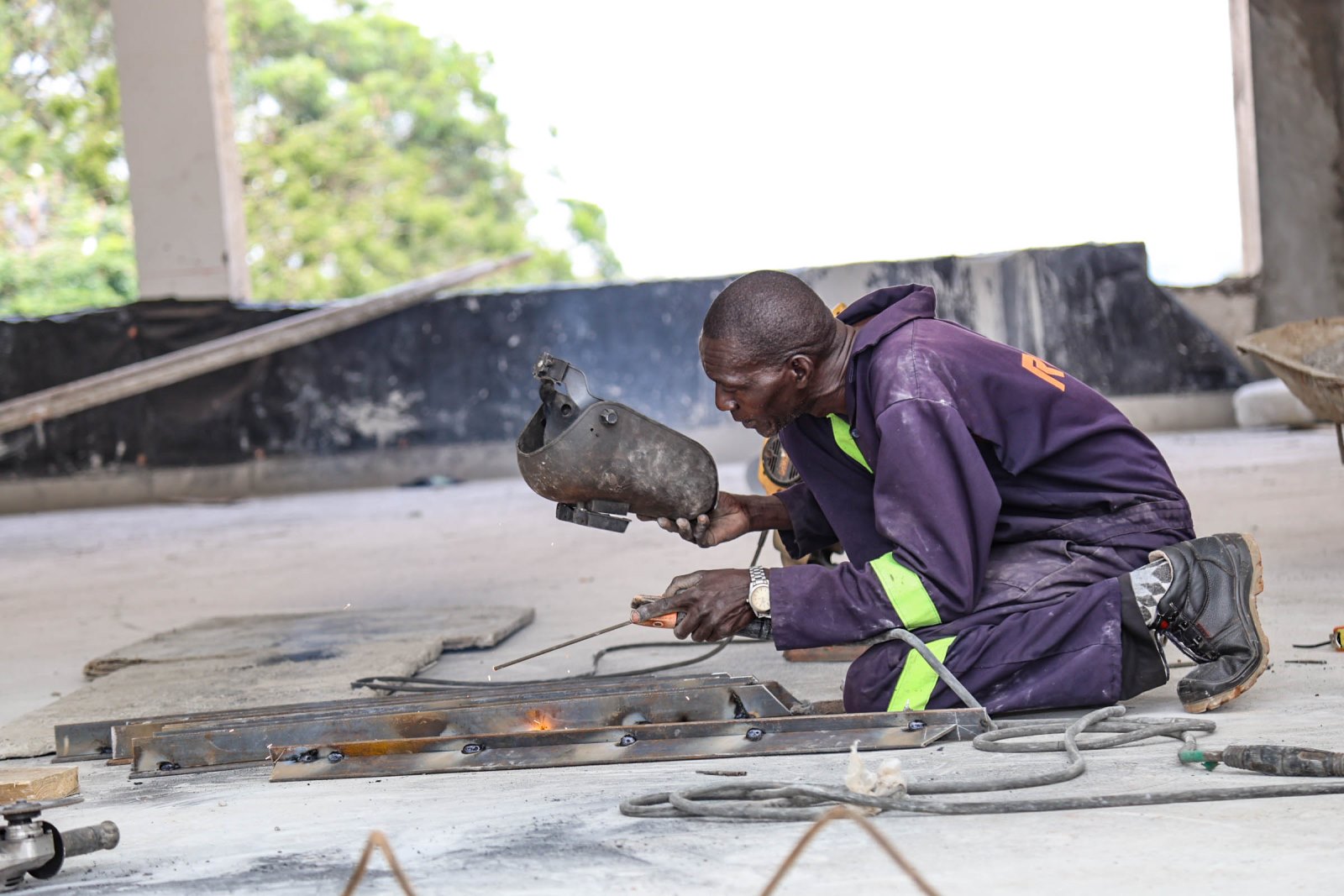 A construction worker undertakes metal fabrication works at the Makerere University School of Public Health (MakSPH) building site. Construction of Phase II of the Makerere University School of Public Health (MakSPH) Complex, Eastern Gate, Main Campus, Kampala Uganda, East Africa.