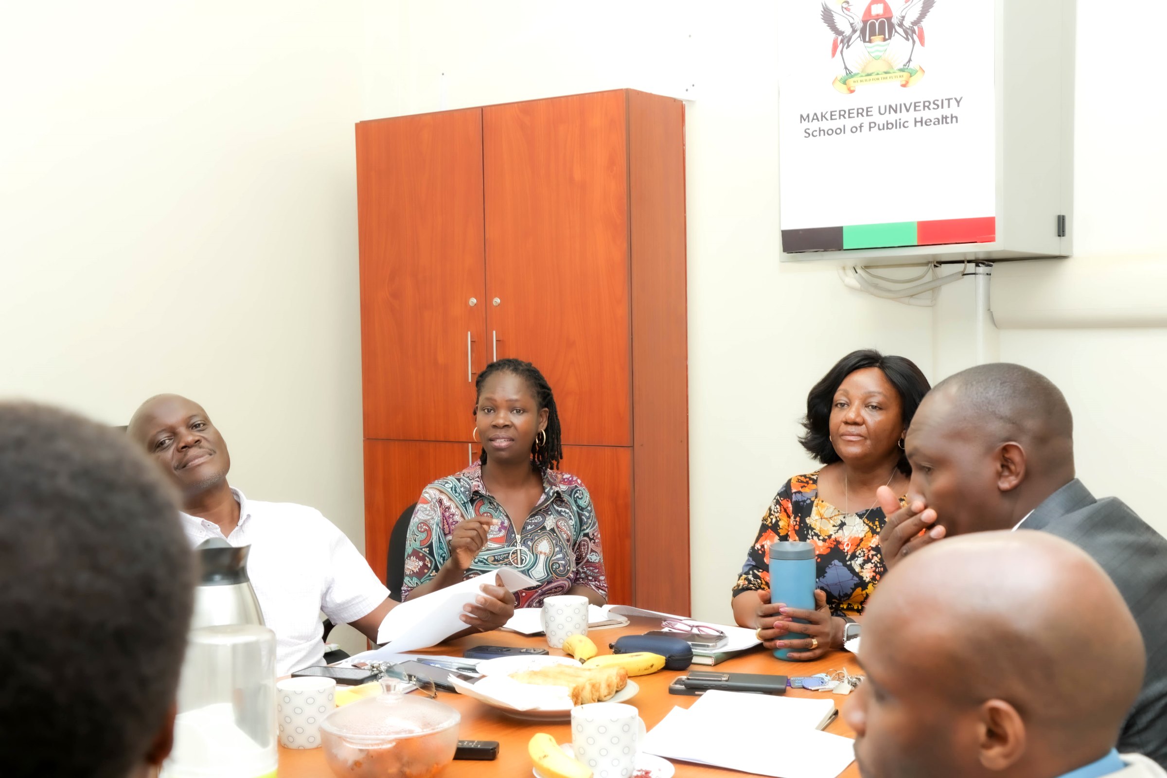 Dr. Joan Mutyoba (centre), Head of the Department of Epidemiology and Biostatistics, speaks at the handover meeting as Prof. Frederick Makumbi (left), Prof. Rhoda Wanyenze, and Mr. Amos Dembe look on. Ms. Gladys Khamili hands over to Ms. Annet Khabuya after 12 years of service as Registrar and transitions to senior role Deputy Registrar, Senate Division, Office of the Academic Registrar during the Makerere University School of Public Health (MakSPH) 239th Management Meeting, 15th April 2026, Mulago Campus, Kampala Uganda, East Africa.