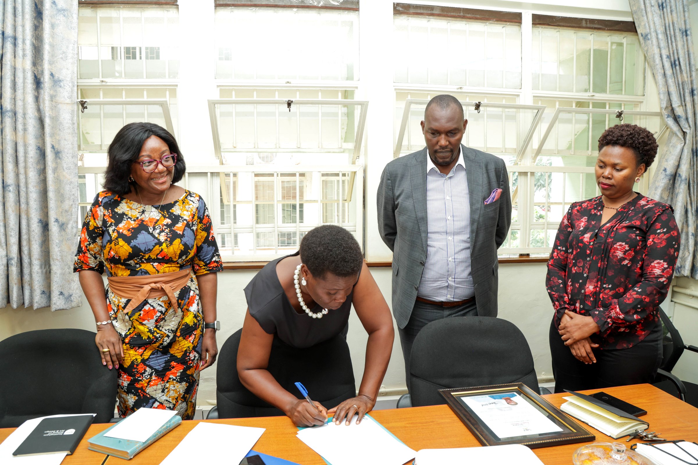 Internal Auditor Mr. Amos Dembe (C) oversaw the handover ceremony. Ms. Gladys Khamili hands over to Ms. Annet Khabuya after 12 years of service as Registrar and transitions to senior role Deputy Registrar, Senate Division, Office of the Academic Registrar during the Makerere University School of Public Health (MakSPH) 239th Management Meeting, 15th April 2026, Mulago Campus, Kampala Uganda, East Africa.