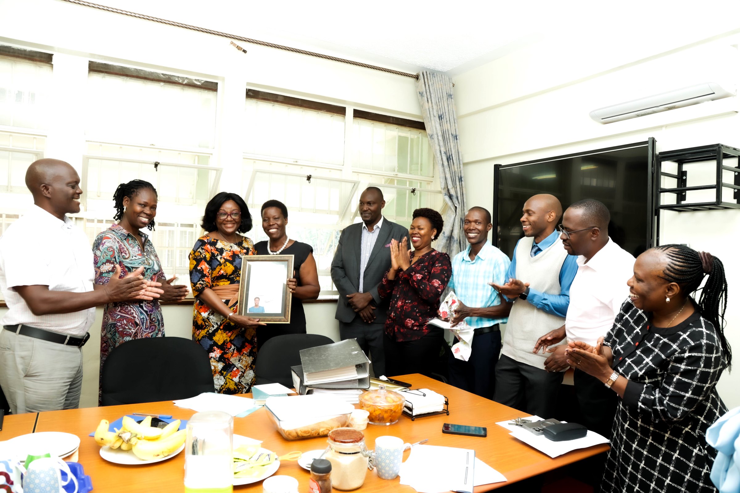Dr. Rhoda Wanyenze presents a plaque to Ms. Gladys Khamili, joined by MakSPH management. Ms. Gladys Khamili hands over to Ms. Annet Khabuya after 12 years of service as Registrar and transitions to senior role Deputy Registrar, Senate Division, Office of the Academic Registrar during the Makerere University School of Public Health (MakSPH) 239th Management Meeting, 15th April 2026, Mulago Campus, Kampala Uganda, East Africa.