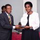 Academic Registrar Prof. Mukadasi Buyinza handing over a plaque in appreciation of Mrs. Patience Rubabinda Mushengyezi.