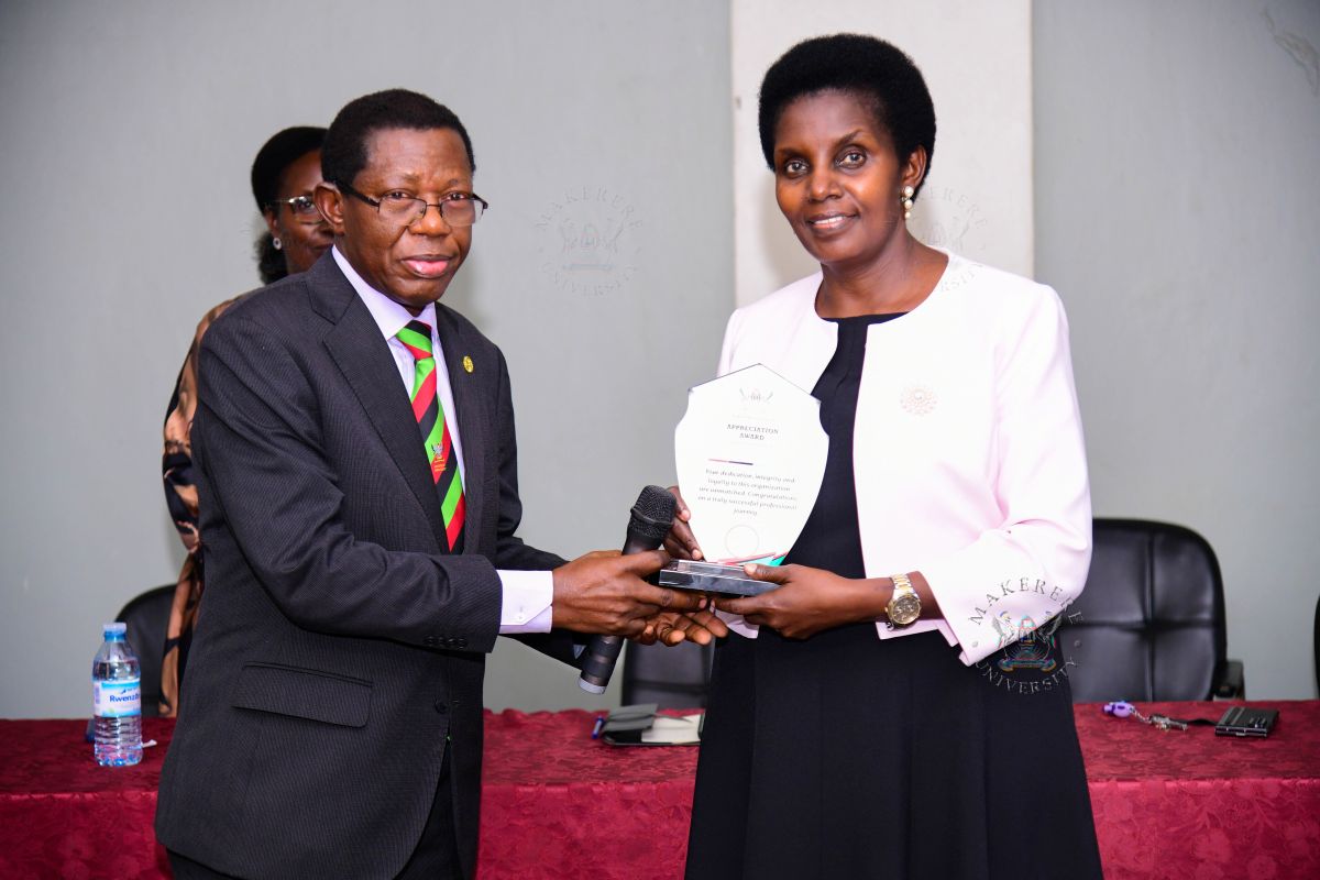 Academic Registrar Prof. Mukadasi Buyinza handing over a plaque in appreciation of Mrs. Patience Rubabinda Mushengyezi.