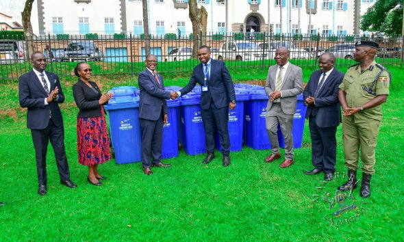 Prof. Barnabas Nawangwe (3rd L) shakes hands with Centenary Bank's Mr. Sunday Julius (C) as L-R: Mr. Simon Kizito, Prof. Sarah Ssali, Prof. Henry Alinaitwe, Mr. Paul Agaba and SSP Kaheebwa Geoffrey applaud on 11th May 2026. Donation of 30 waste bins by Centenary Bank’s Makerere Branch as part of ESG objectives, 11th May 2026, Freedom Square, Makerere University, Kampala Uganda.