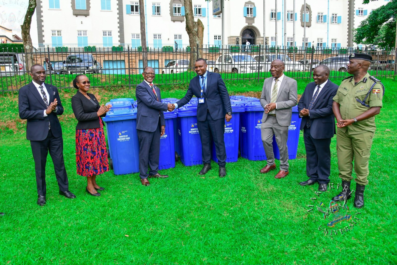 Prof. Barnabas Nawangwe (3rd L) shakes hands with Centenary Bank's Mr. Sunday Julius (C) as L-R: Mr. Simon Kizito, Prof. Sarah Ssali, Prof. Henry Alinaitwe, Mr. Paul Agaba and SSP Kaheebwa Geoffrey applaud on 11th May 2026. Donation of 30 waste bins by Centenary Bank’s Makerere Branch as part of ESG objectives, 11th May 2026, Freedom Square, Makerere University, Kampala Uganda.
