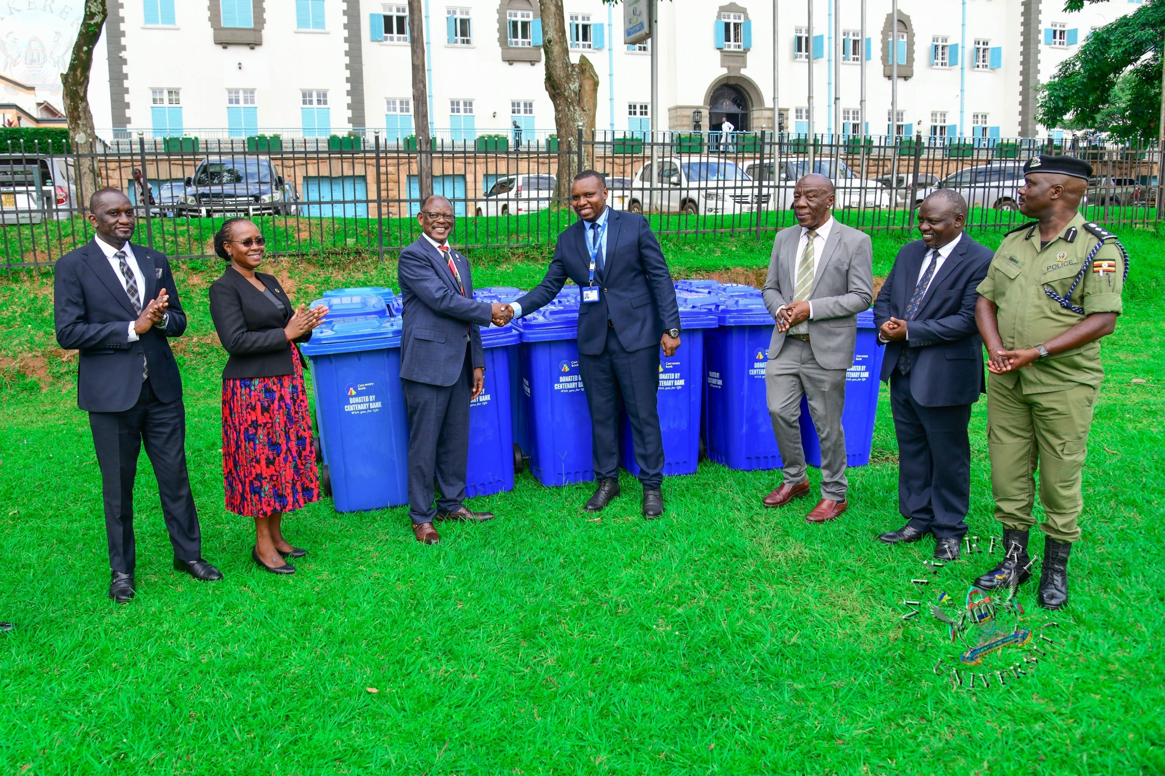 Prof. Barnabas Nawangwe (3rd L) shakes hands with Centenary Bank's Mr. Sunday Julius (C) as L-R: Mr. Simon Kizito, Prof. Sarah Ssali, Prof. Henry Alinaitwe, Mr. Paul Agaba and SSP Kaheebwa Geoffrey applaud on 11th May 2026. Donation of 30 waste bins by Centenary Bank’s Makerere Branch as part of ESG objectives, 11th May 2026, Freedom Square, Makerere University, Kampala Uganda.