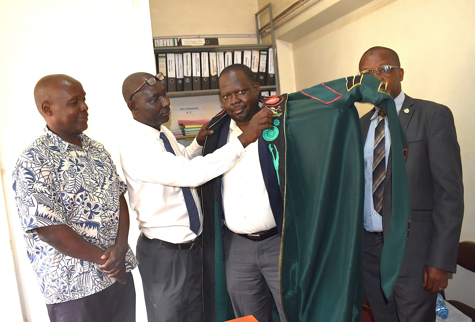 Mr. Patrick Akonyet robing Prof. Ssevviiri in the Dean’s academic regalia. Prof. Michael Owor officially hands over office of Dean, School of Physical Sciences to Prof. David Ssevviiri for the next four years, effective 6th May 2026, on 28th May 2026, College of Natural Sciences (CoNAS), Makerere University, Kampala Uganda, East Africa.