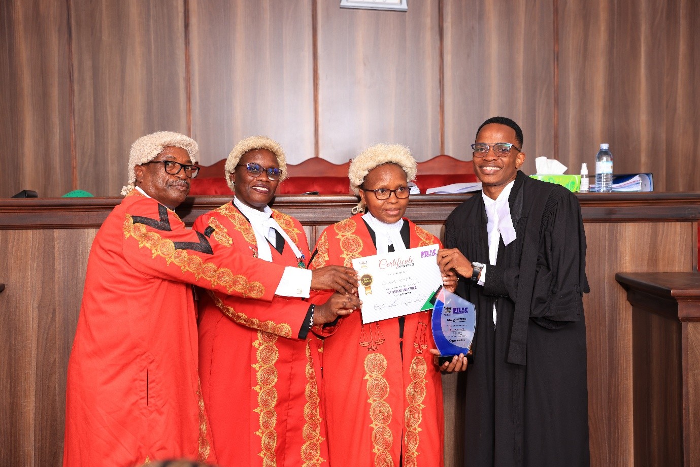 L-R: The presiding judges - Hon Justice Isa Serunkuma, Hon. Lady Justice Jane Okuo Kajuga, Hon Lady Justice Alice Komuhangi Khauka with Mayanja Owen who was named the best oralist at the moot competition. Public Interest Law (PILAC) 13th Clinical Legal Education (CLE) Moot presided over by a panel of three High Court Judges: Hon. Lady Justice Jane Okuo Kajuga, Hon. Justice Isa Serunkuma and Hon. Lady Justice Alice Komuhangi Khaukha, 14th May 2026, in the Makerere University School of Law (SoL) Moot Court Room, Kampala Uganda, East Africa.