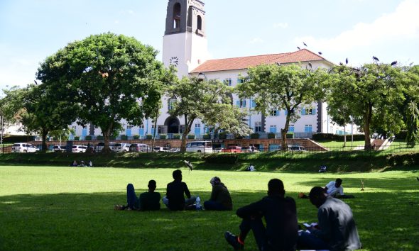 Student discussion groups converge in tree shades on the edges of the Freedom Square overlooked by the Main Building. Makerere University, Kampala Uganda, East Africa.