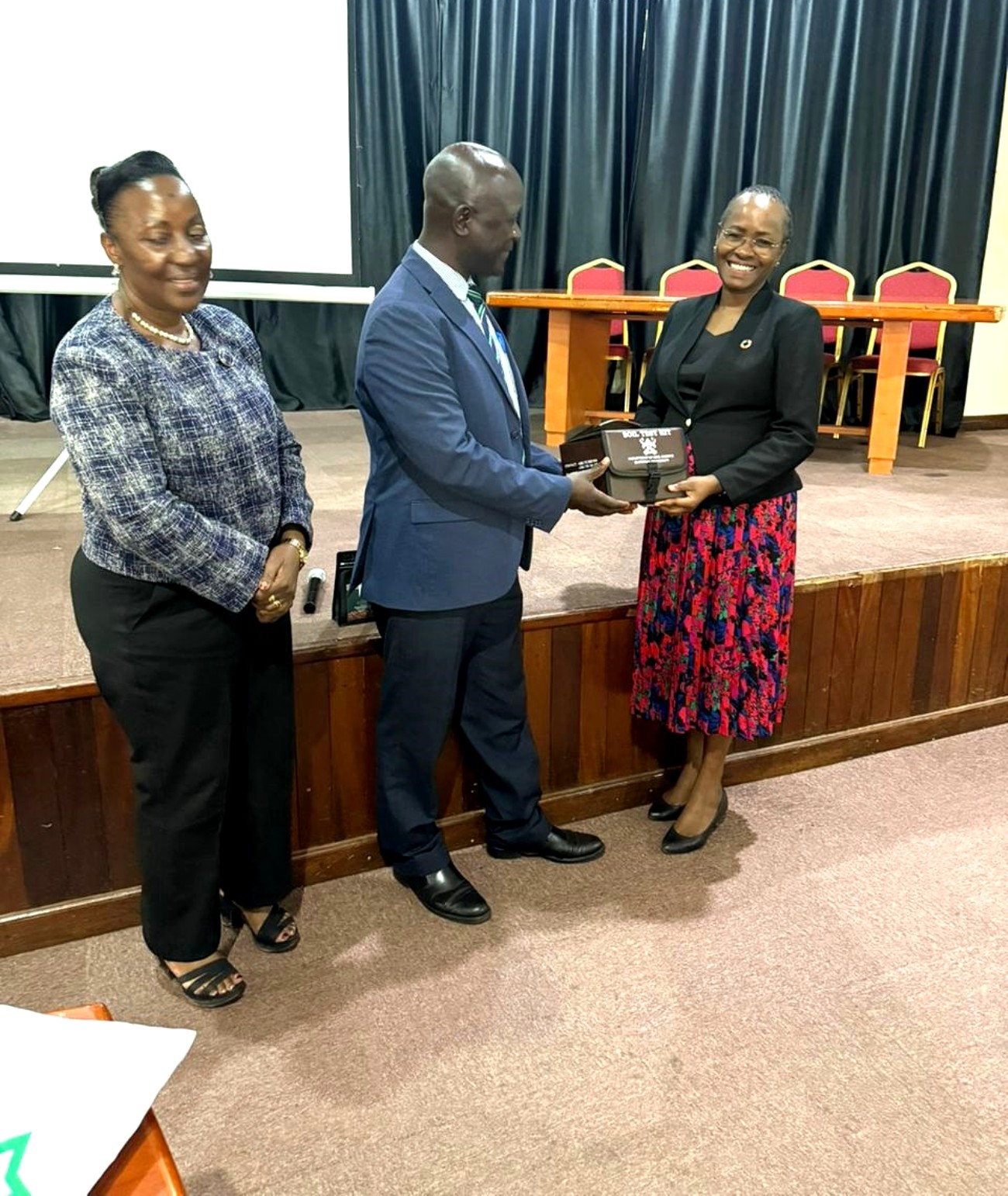 The Deputy Principal, Prof. Yazidhi Bamutaze handing over the soil test kit to Prof. Sarah Ssali. Management strategic engagement with staff at the College of Agricultural and Environmental Sciences (CAES), 11 May 2026, Conference Hall, School of Food Technology, Nutrition and Bioengineering, Makerere University, Kampala Uganda.