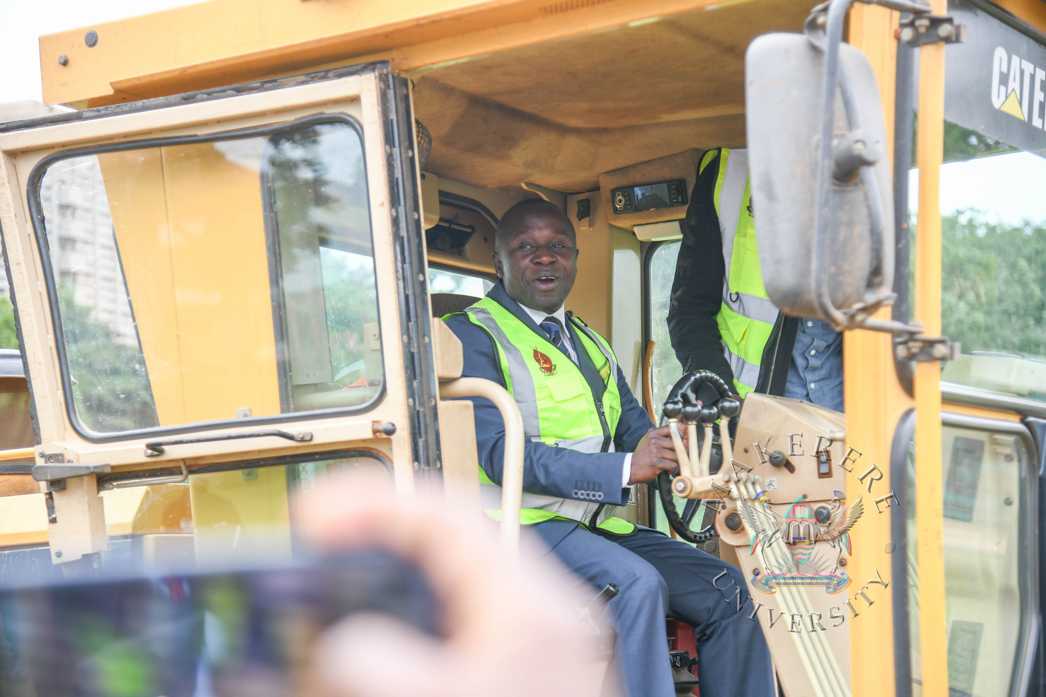 Hon. Peter Ogwang breaks ground with a grader. Groundbreaking ceremony for the AFCON 2027 training facilities at Makerere University and commissioning of six construction sites in Hoima, Masindi, Kyambogo University, Lira University, and Gulu University, 19th February 2026, Main Sports Grounds, Kampala Uganda, East Africa.