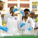 Cover page of the College of Natural Sciences (CoNAS) Annual Report 2025. Depicting Students in a lab with the JICA Building as a background image, Makerere University, Kampala Uganda, East Africa.