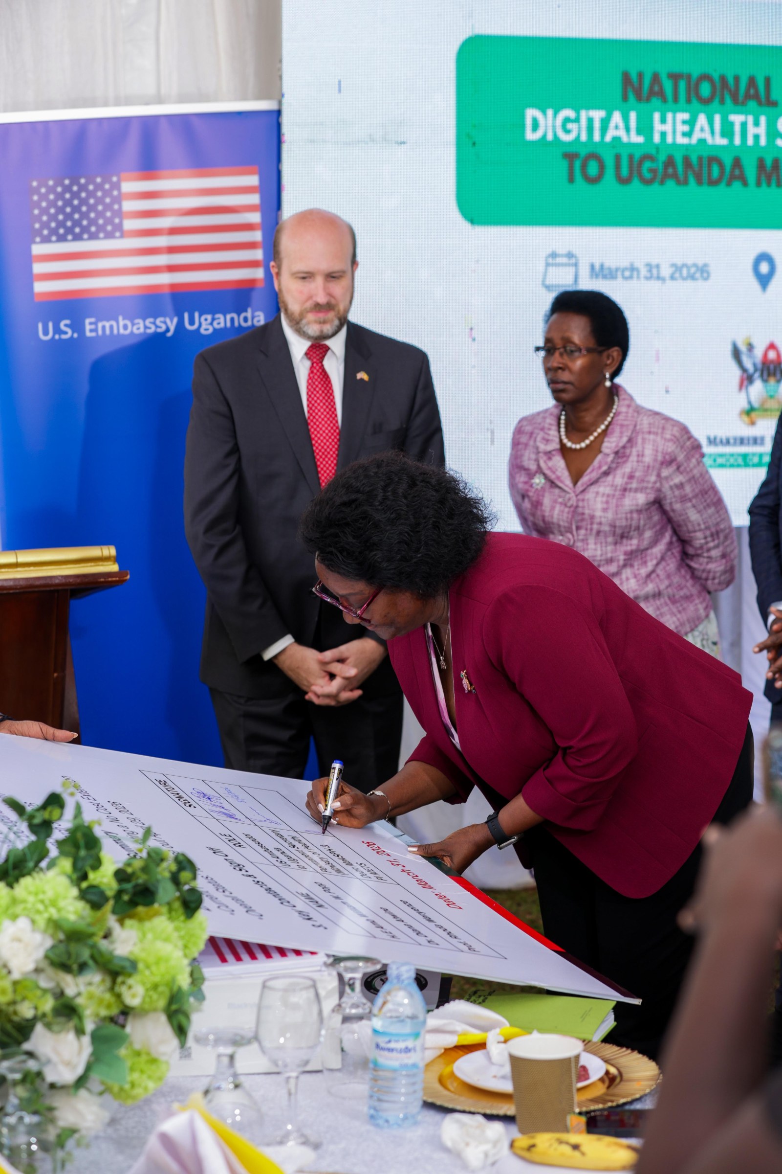 MakSPH Dean Prof. Rhoda Wanyenze signs the METS handover board during the transition of digital health systems and assets to the Ministry of Health on 31 March 2026, as then U.S. Ambassador to Uganda H.E. William W. Popp and Dr. Diana Atwine, Permanent Secretary, Ministry of Health, look on. Makerere University School of Public Health (MakSPH) reflection on long and productive partnership with the people and Government of the United States, spanning more than 35 years. Kampala Uganda, East Africa.
