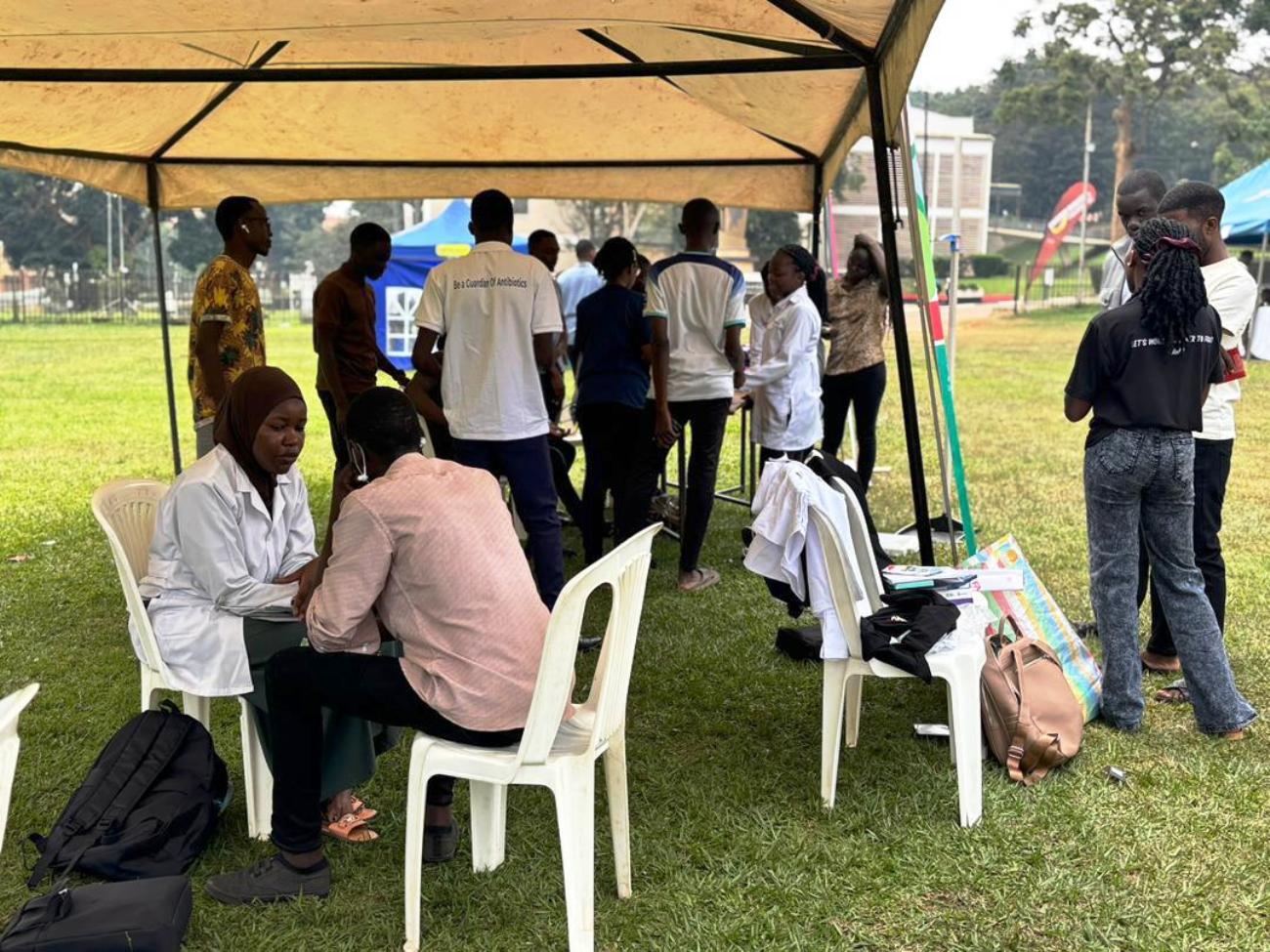 A female medical personnel attends to a male client. The 91st Guild Ministry of Health Annual Makerere Guild Medical Camp, 3rd and 4th October 2025, Freedom Square, Makerere University, Kampala Uganda, East Africa.
