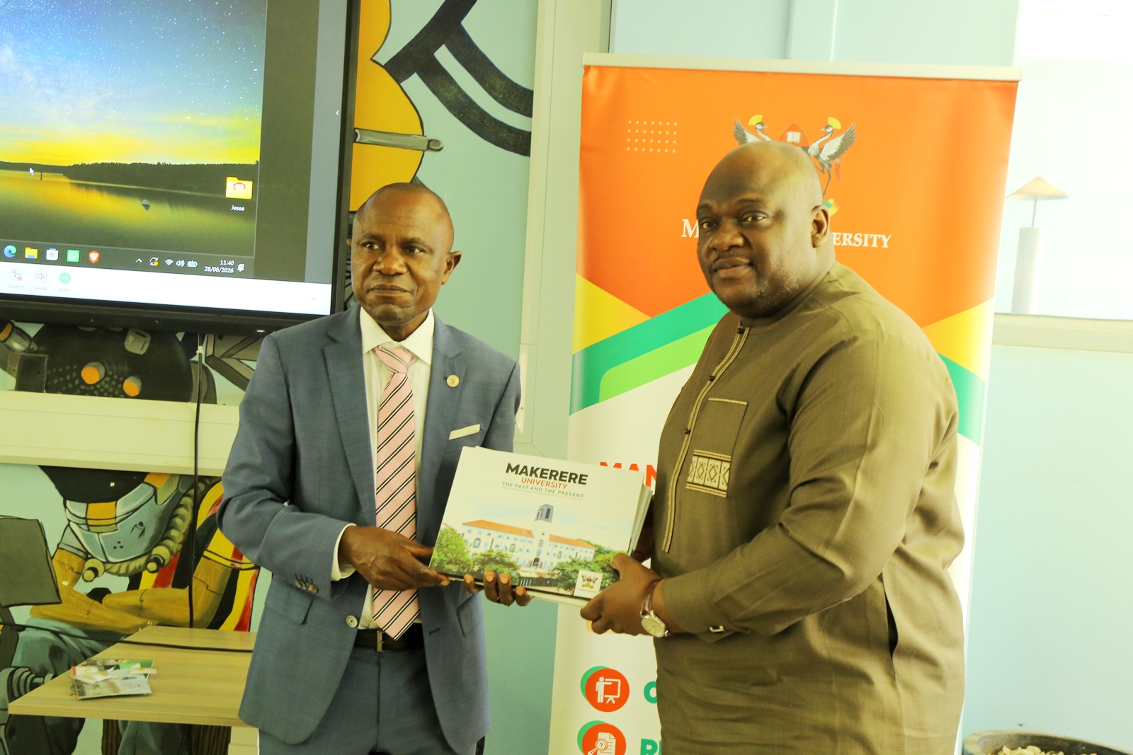 Prof. Eria Hisali (L) presents Makerere's Souvenir Coffee Table Book to Mr Baboucarr Jobe (R). Public Investment Management (PIM) Centre of Excellence hosts high-level delegation from The Gambia led by Mr Baboucarr Jobe, Permanent Secretary in The Gambia’s Ministry of Finance, 28th August 2026, Makerere University, Kampala Uganda, East Africa.