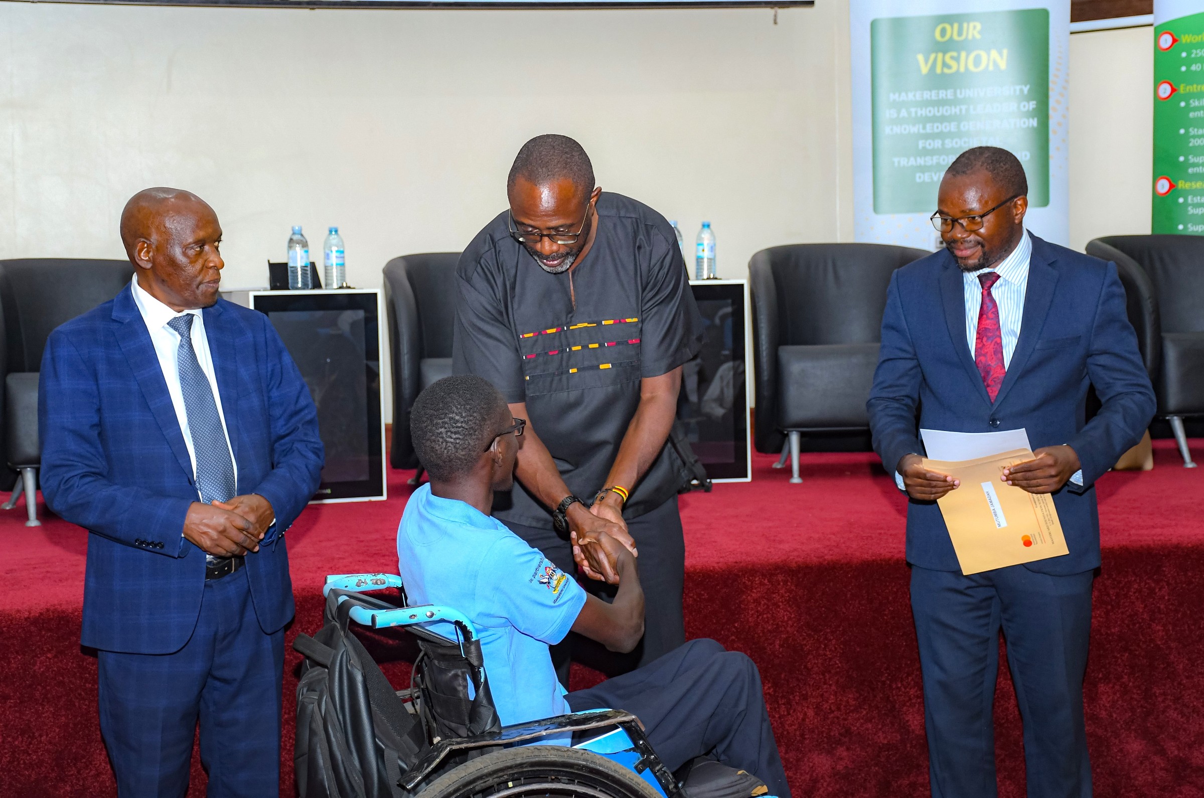 L-R: Mr. Charles Ssentongo, Mr. Adrian Bukenya, and Prof. Ibrahim Okumu, awarding one of the Scholars. Award Ceremony for Cohort 9 of 258 recipients of the prestigious Mastercard Foundation scholarship for the 2026/2027 academic, 20th August 2026, Makerere University School of Public Health (MakSPH) Auditorium, Main Campus, Kampala Uganda, East Africa.