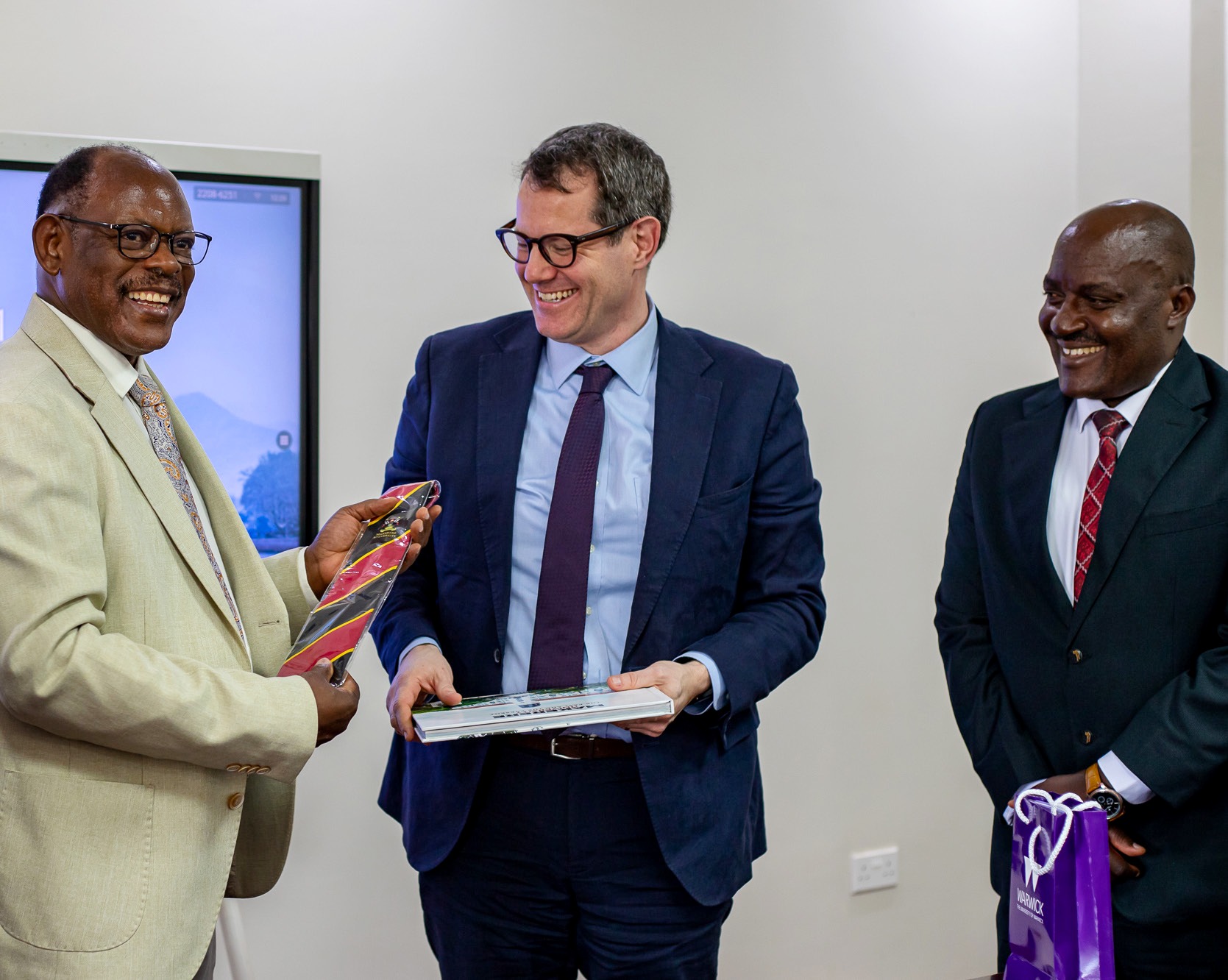 Prof. Barnabas Nawangwe (L) presents Prof. Daniel Branch (C) with the Makerere necktie and Makerere@100 Coffee Table Book as Prof. Fred Masagazi Masaazi (R) witnesses during his visit on 13th February 2026. Makerere University, Kampala Uganda, East Africa.