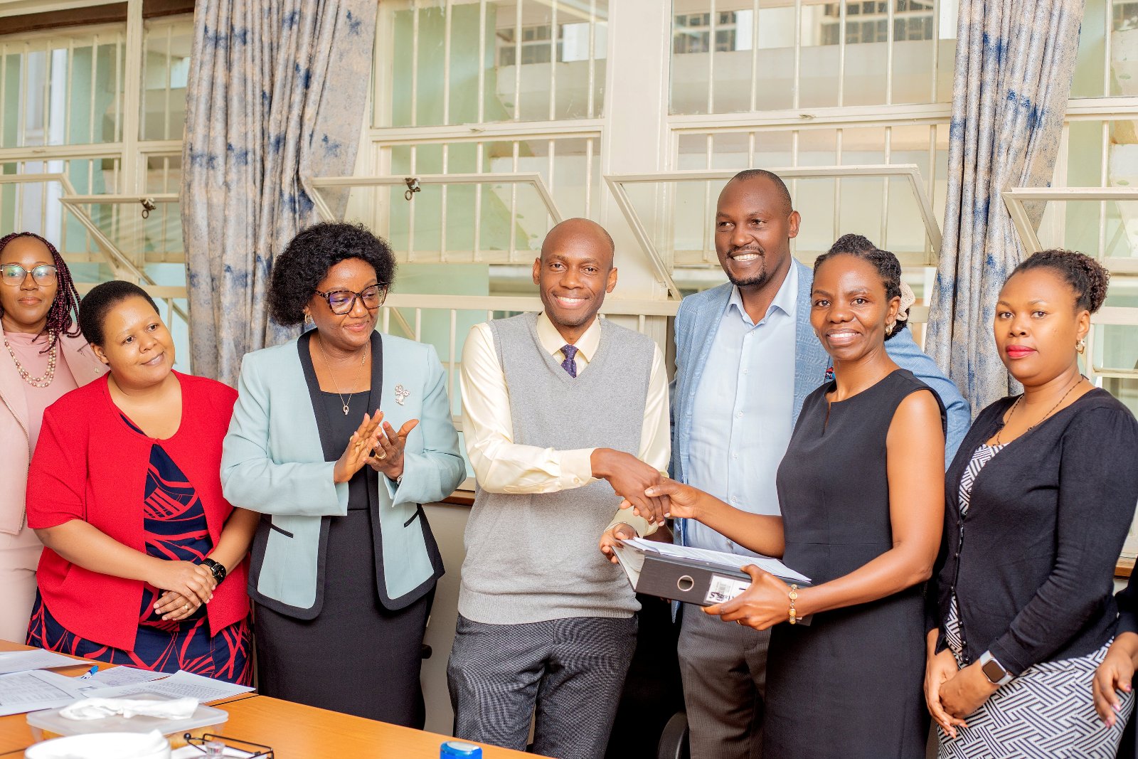 Officials witness as Dr. David Musoke and Dr. Esther Buregyeya shake hands at the handover ceremony on 11th August 2026. Makerere University School of Public Health (MakSPH) leadership transition, Department of Disease Control and Environmental Health, Dr. David Musoke takes over from Dr. Esther Buregyeya, 11th August 2026, Mulago Hospital Complex, Kampala Uganda, East Africa.