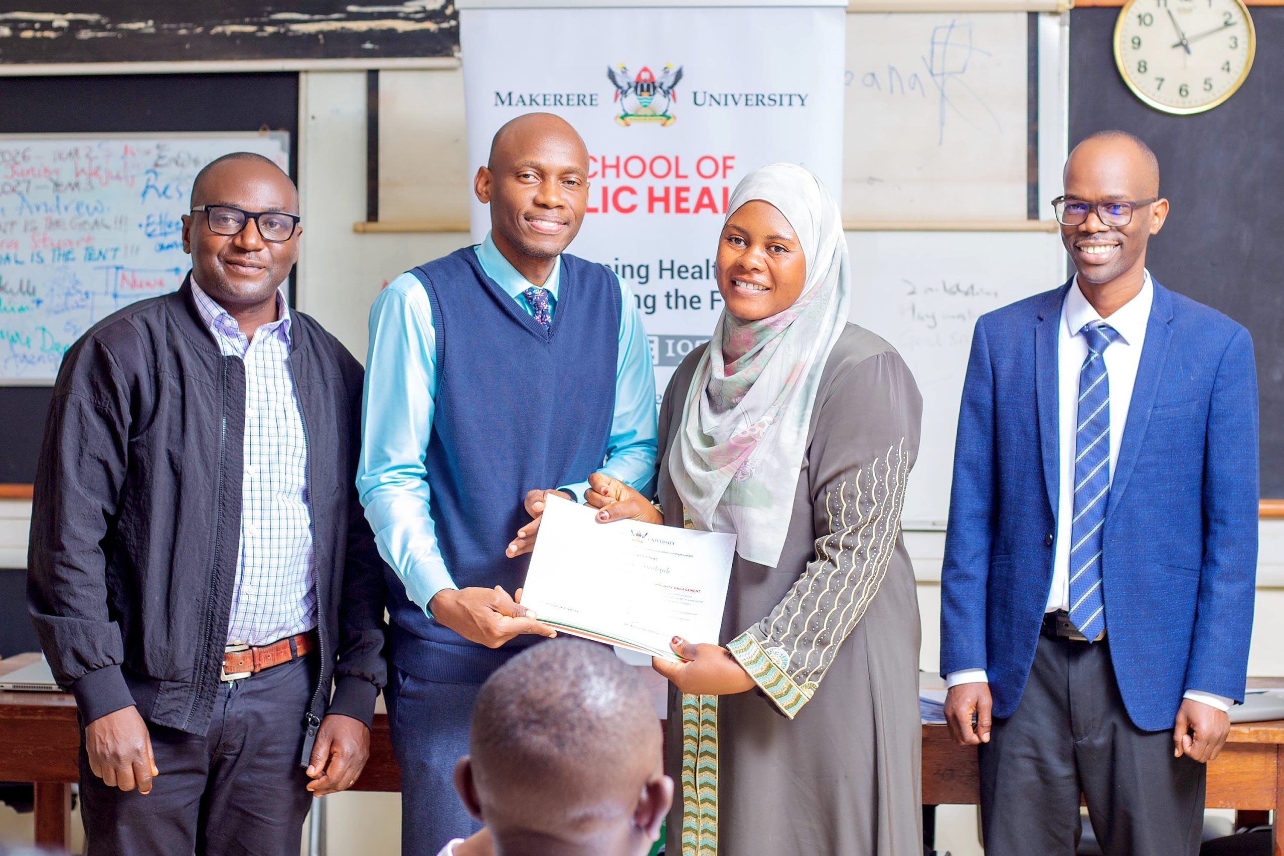 Assoc. Prof. David Musoke presents a certificate to one of the participants. Makerere University School of Public Health (MakSPH) and Department of Journalism and Communication (DJC), College of Humanities and Social Sciences (CHUSS) graduation of 33 professionals from the second cohort of the Certificate in Health Communication and Community Engagement, 31st July 2026, Mulago Hospital Complex, Kampala Uganda, East Africa.
