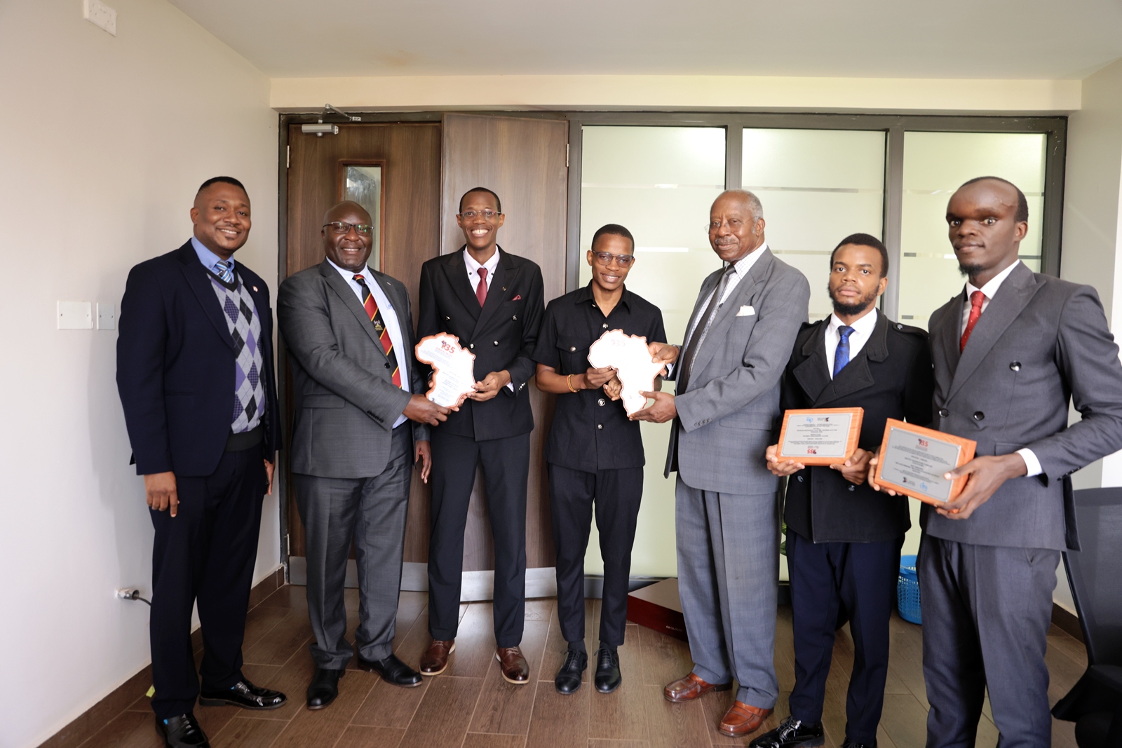 Makerere University School of Law (SoL) 1st Runners-Up in the week-long (26 July to 2 August 2026) 35th Christof Heyns All Africa Human Rights Moot Court Competition, Institut Universitaire d’Abidjan in Abidjan, Côte d’Ivoire, West Africa. Conrad and Owen present their trophies to Professor Ronald Naluwairo (2nd left), Dean – SoL and Hon. Justice Stephen Egonda Ntende (3rd right), Rtd Justice of the Court of Appeal of Uganda. Also present are Dr. Daniel Ruhweza (1st left), John Baptist Katende (2nd right), Chairperson Makerere Mooting Society and Rogers Sembajjwe (1st right), President – Makerere University Law Society.