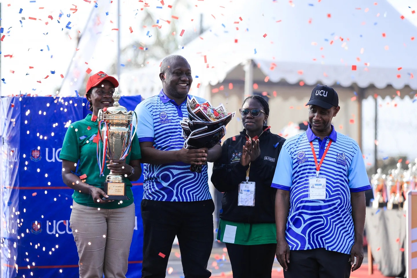 The Dean of Students, Dr. Winifred Kabumbuli (with the trophy) and Deputy Dean In-Charge of Sports, Brian Miiro (with the flowers) as they received the third overall prize at the AUUS Games on behalf of team Makerere. Sports and Recreation Department, Makerere University, Kampala Uganda, East Africa.