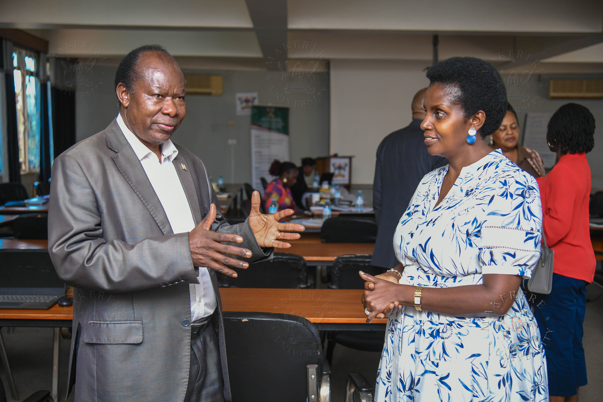 Prof. Fredrick Jones Muyodi (L) chats with Mrs. Patience Mushengyezi. Makerere University Writing Center (MakWC) minutes writing toolkit workshop for executive and administrative staff, opened by DVCAA Prof. Sarah Ssali, 4th August, 2026, Telepresence Hall, Senate Building, Makerere University, Kampala Uganda, East Africa.