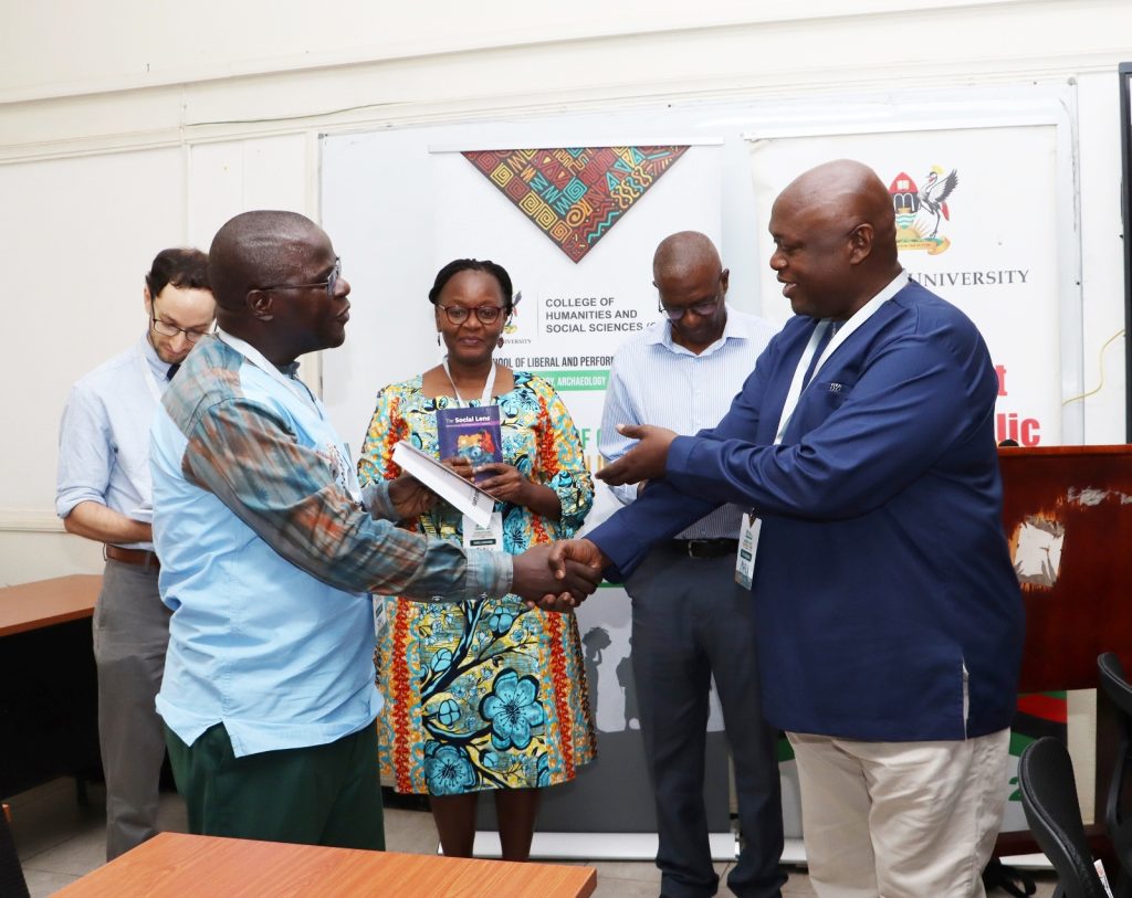 Dr. Anthony Mugeere giving a copy of his new book to the Deputy Principal. Opening Ceremony of three-day workshop hosted by the Department of History, Archaeology and Heritage Studies, School of Liberal and Performing Arts, College of Humanities and Social Sciences (CHUSS) examining the historical relationship between climate change and migration in Uganda, under a joint project between Makerere University and the University of Cambridge, CHUSS Smart Room, 8th-10th September 2026, Kampala Uganda, East Africa.