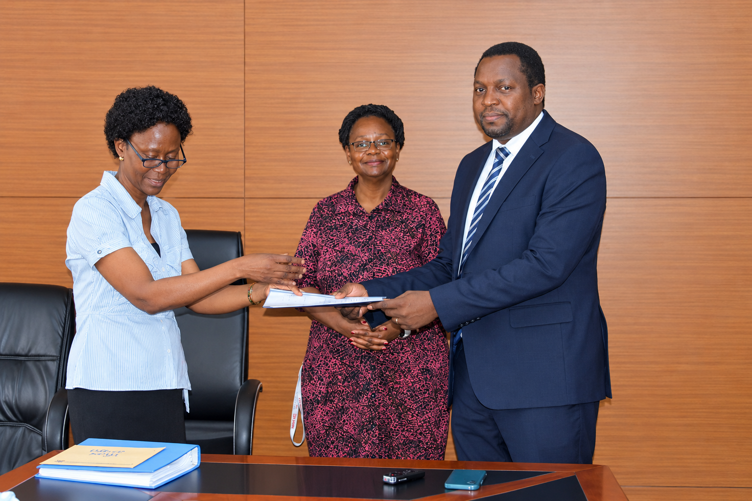 Outgoing Head of Department, Assoc. Prof. Robinah Kulabako (left), hands over the office to the incoming Head of Department, Dr. Philip Nyenje, during a ceremony held at CEDAT on October 5, 2026. In the centre is the Dean, School of Engineering, Assoc. Prof. Eng. Dorothy Okello